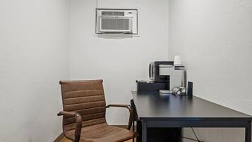 A conference room with a brown leather chair, a dark table, a white air conditioning unit, and a coffee machine.
