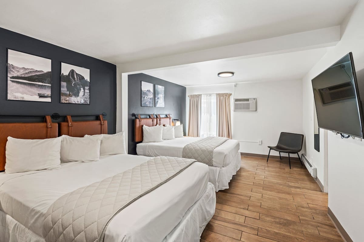 A hotel room with two beds, a TV, and artwork on the wall.