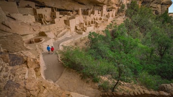 Un cañón con antiguas viviendas rupestres y un sendero estrecho.