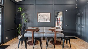 A modern interior with a dark wall, a large map, and a sofa with two round tables and stools.