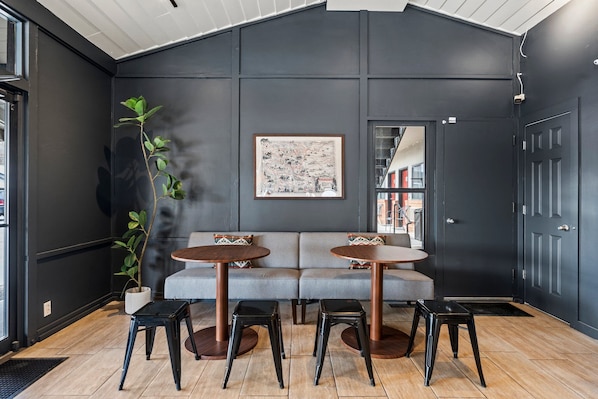 A modern interior with a dark wall, a large map, and a sofa with two round tables and stools. - Adventure Inn Durango (Durango)