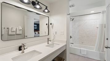 A modern bathroom with dual sinks, a large mirror, and a shower area.