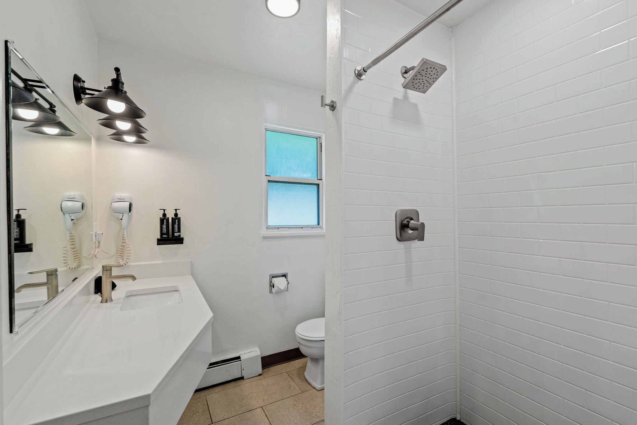 A bathroom with a white sink, two mirrors, a toilet, and a shower.