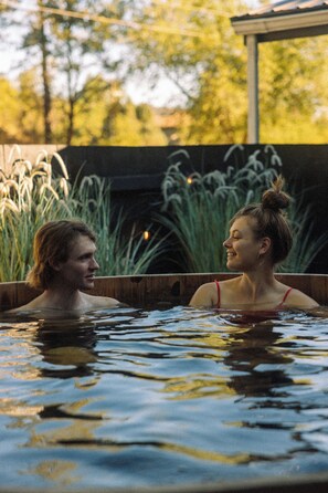 A couple in a hot tub with a wooden deck and tall grasses in the background. - Adventure Inn Durango (Durango)