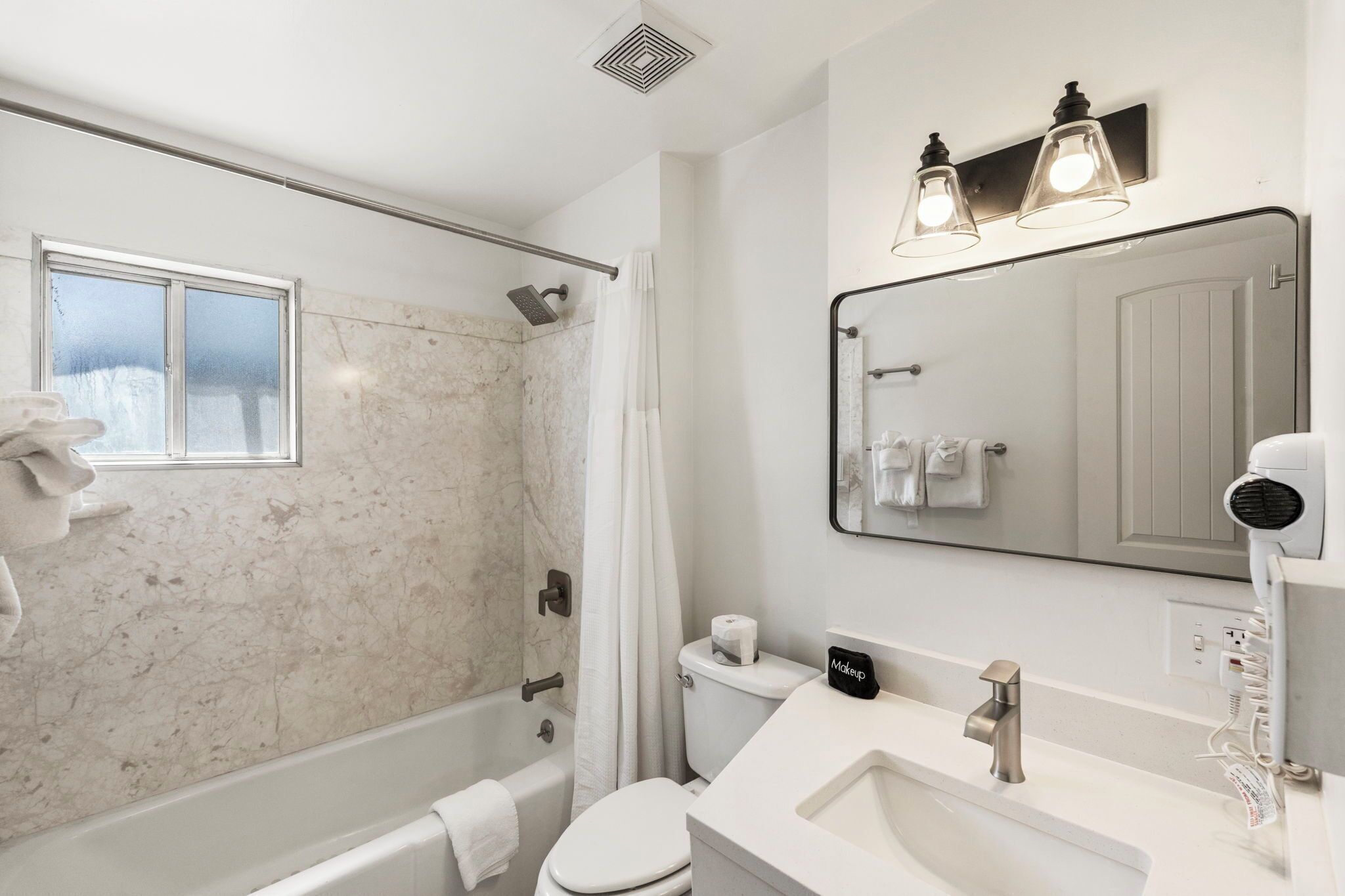 A modern bathroom with a shower, toilet, sink, and a large mirror.