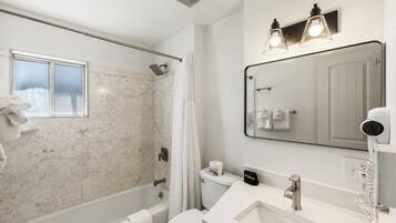 A modern bathroom with a shower, toilet, sink, and a large mirror.