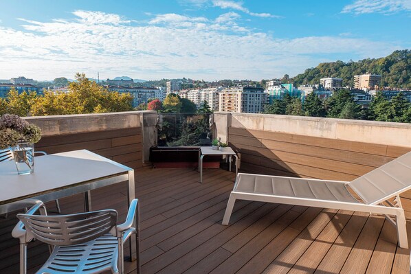 A rooftop terrace with a table, chairs, and a lounge area. - Eurostars Amara (San Sebastián)