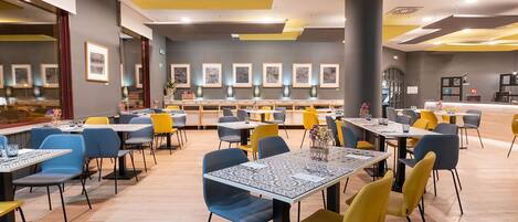 A modern dining area with multiple tables and chairs, a counter with a menu, and framed artwork on the walls.