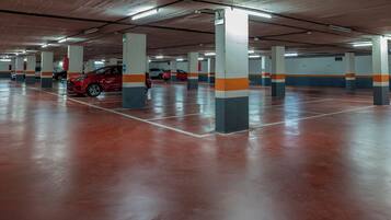 Un estacionamiento de varios niveles con pilares de concreto y un coche rojo estacionado en una de las bahías.