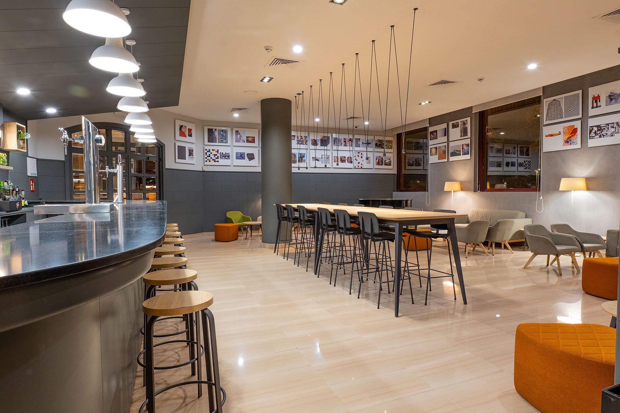 Uma área de bar moderna com um balcão extenso, vários bancos e uma variedade de opções de assento, incluindo bancos altos e cadeiras estofadas.