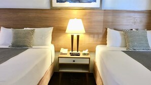 A hotel room with two beds, a nightstand with a lamp, and a framed picture on the wall. - San Diego Downtown Lodge (San Diego)