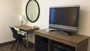 A hotel room with a desk, a flat-screen TV, a telephone, a mirror, and a microwave. - San Diego Downtown Lodge (San Diego)