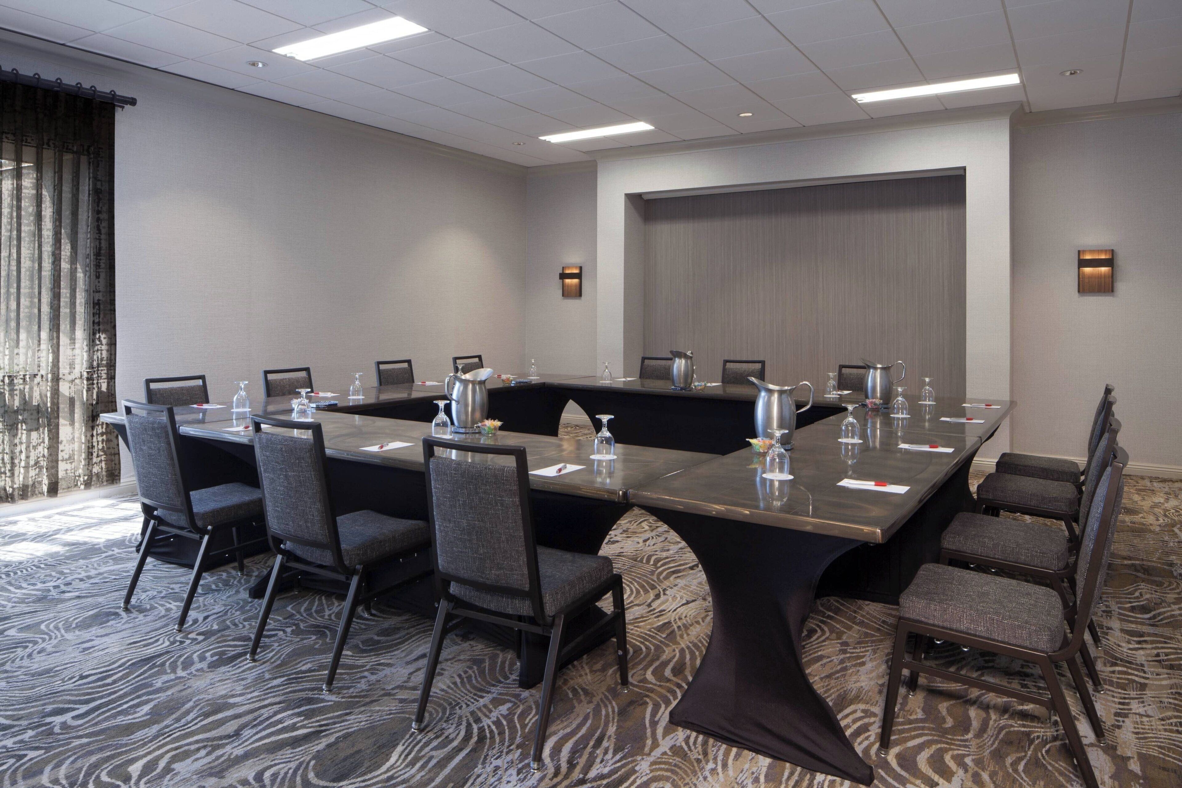 A conference room with a large table, chairs, and a carpeted floor.