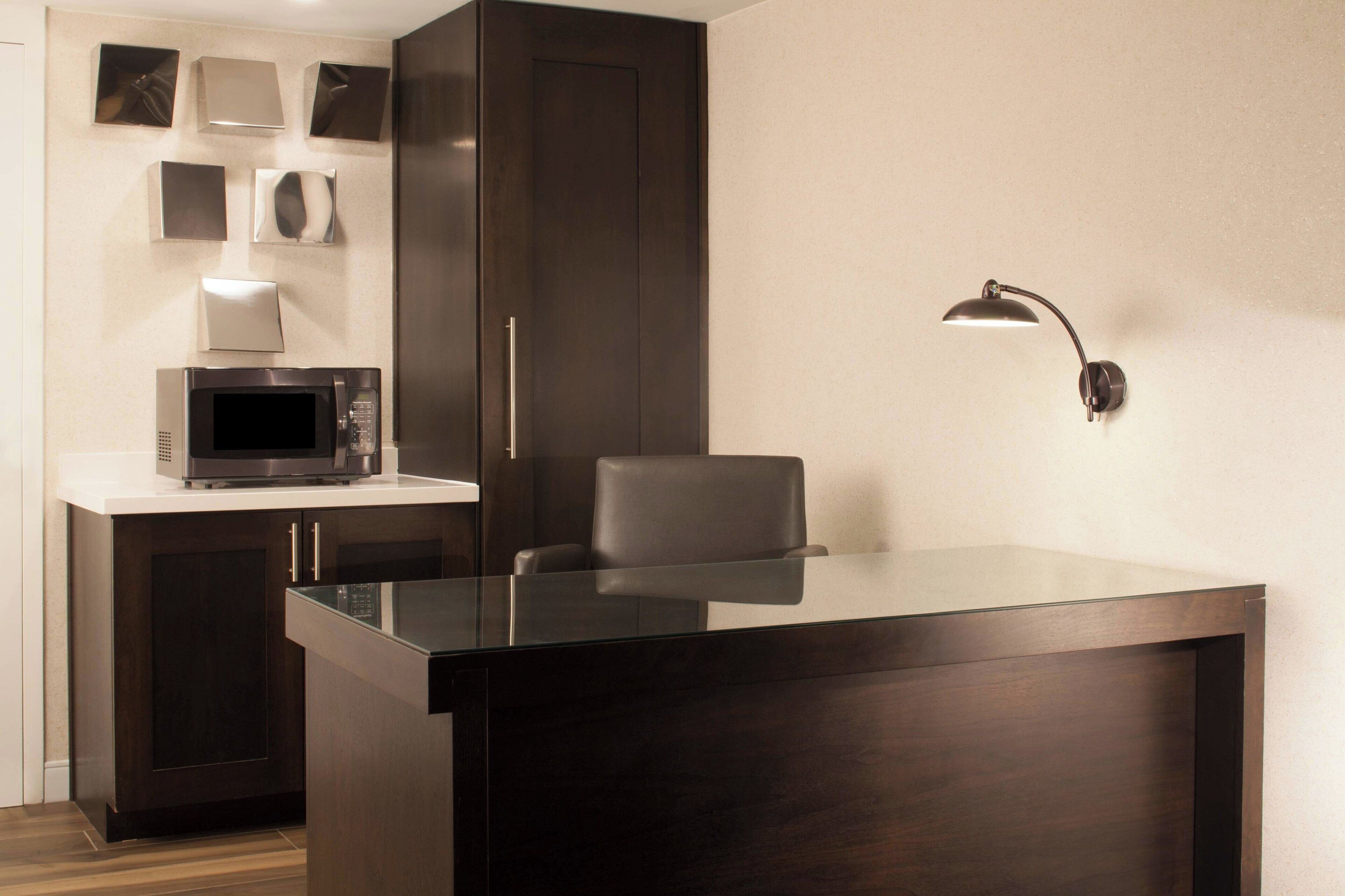 Una cocina moderna con un armario de madera oscura, un microondas y una isla con encimera de vidrio.