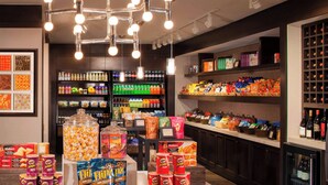 A well-lit store with various snack and beverage options, including a large popcorn dispenser and shelves stocked with bottled drinks.