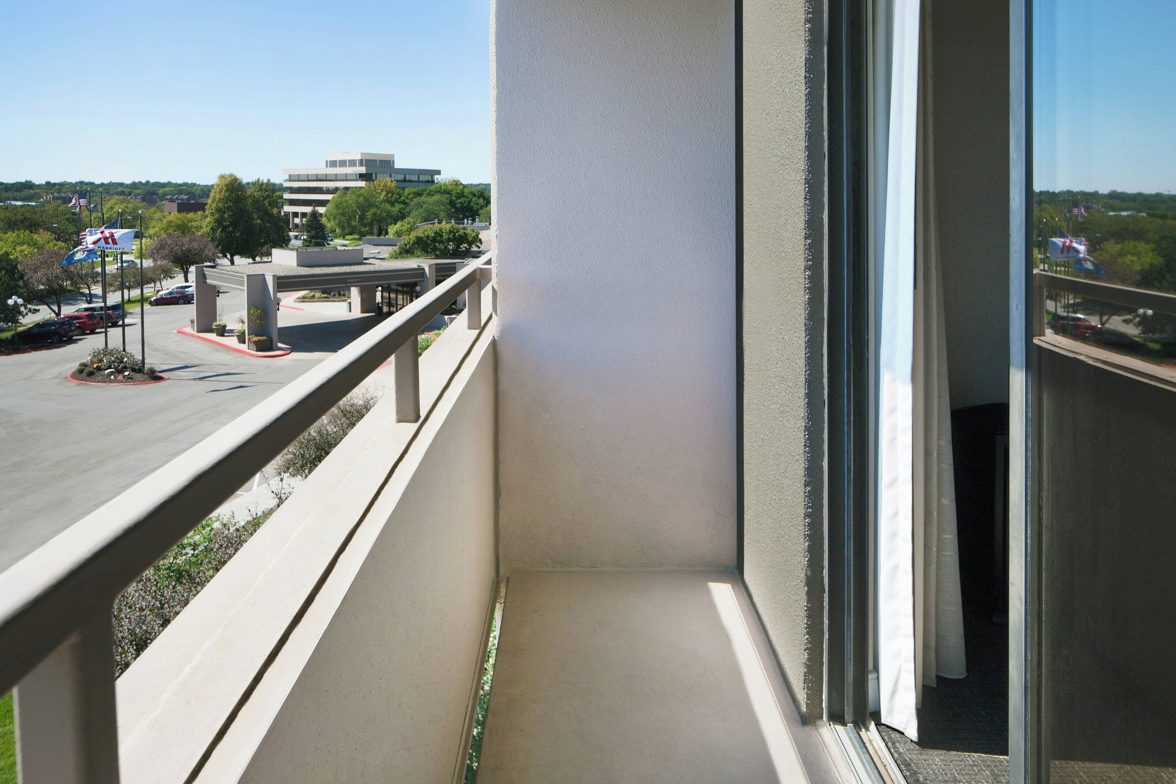 Un balcón con vista despejada a un estacionamiento y un edificio al fondo.