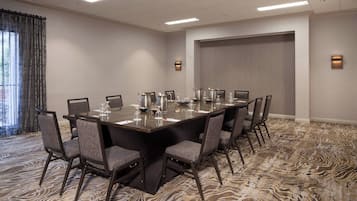 A conference room with a large rectangular table, multiple chairs, and a patterned carpet.