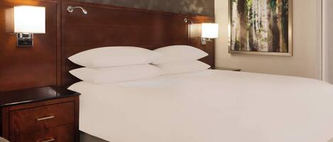 A hotel room with a large bed, two bedside tables with lamps, a nightstand, and a painting on the wall.