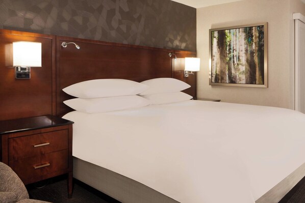 A hotel room with a large bed, two bedside tables with lamps, a nightstand, and a painting on the wall.