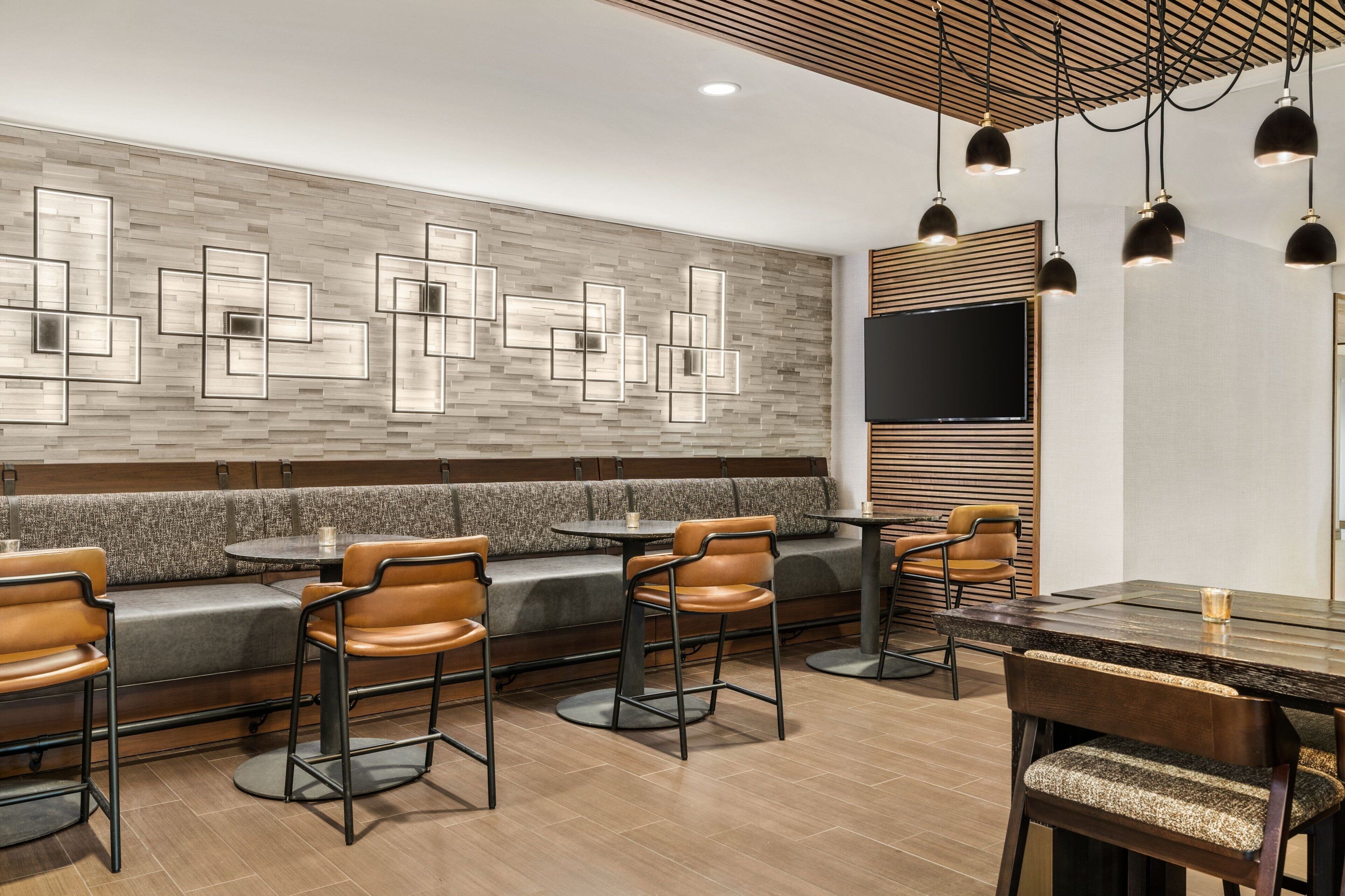 Un restaurant moderne avec un mur en bois, des sièges rembourrés et des luminaires suspendus.