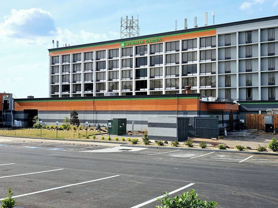 A multi-story building with a sign reading "Wyndham Garden." It features a modern architectural design with a mix of brick and glass facade.