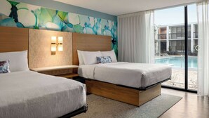 A hotel room with two beds, a large window with a view of a swimming pool, and a colorful abstract mural on the wall. - Wyndham Garden Atlanta Airport (College Park)