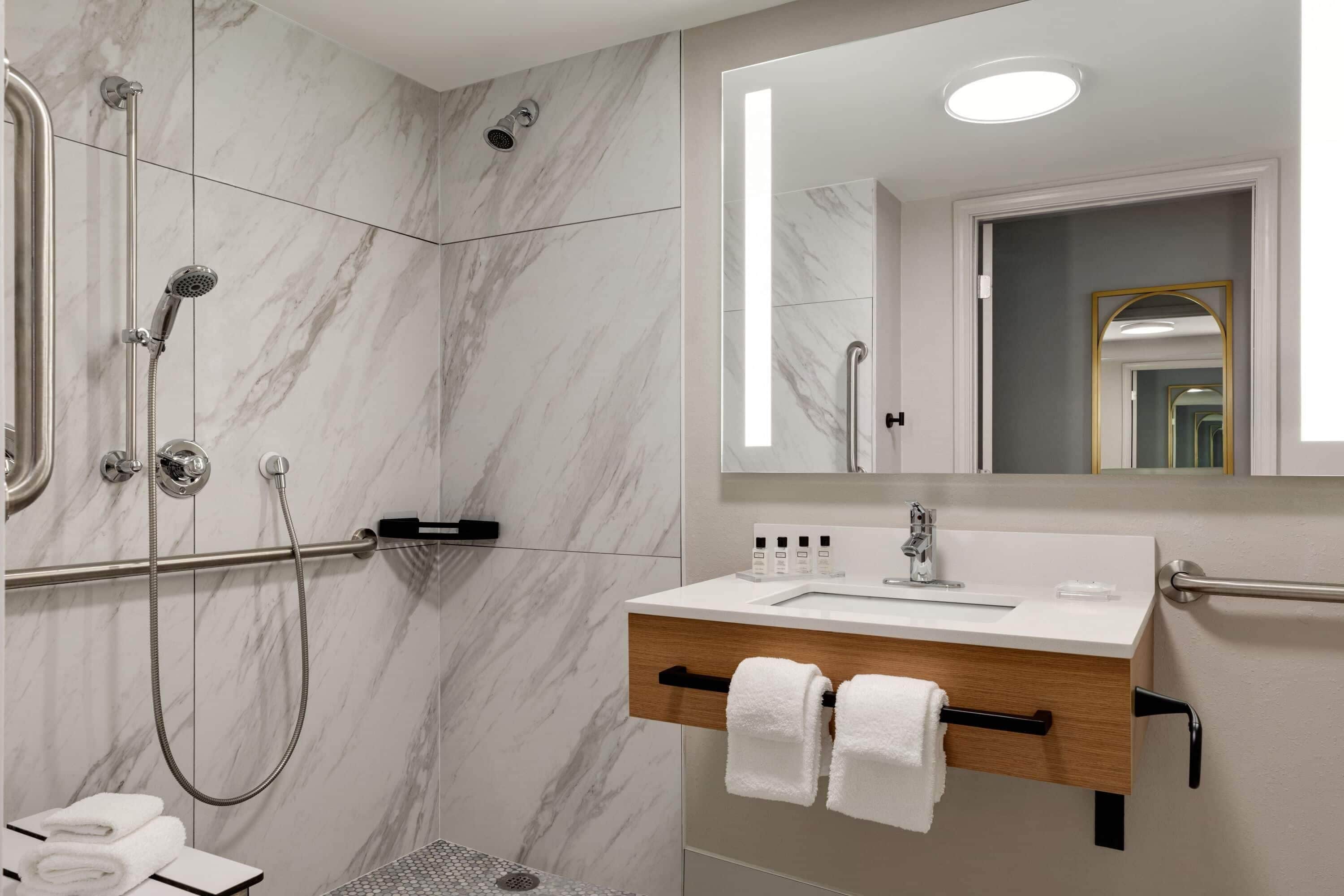 Une salle de bain moderne avec une douche à l’italienne, un meuble-lavabo avec miroir et un porte-serviettes.