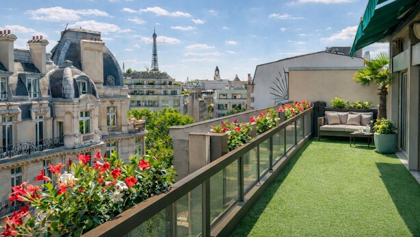 Una terraza en la azotea con césped artificial, un sofá y plantas en macetas.
