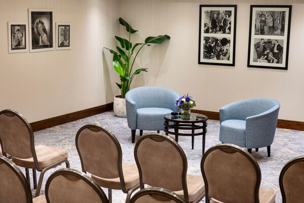 A conference room with a round table, two blue armchairs, and a potted plant.