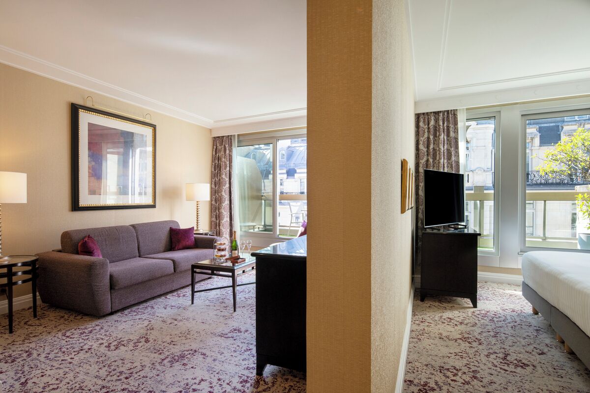 Una habitación de hotel con sofá, mesa de centro, televisión y cama.