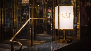 Un interior moderno con puerta de vidrio, una lámpara dorada con un símbolo de corona y una encimera de mármol.