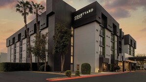 A modern hotel with a courtyard, featuring a flat roof, large windows, and a prominent sign.