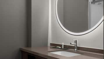 A modern bathroom with a rectangular sink, a round mirror, and a chrome faucet.