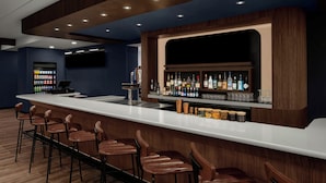 A bar area with a long counter, multiple stools, and a well-stocked bar with various bottles.