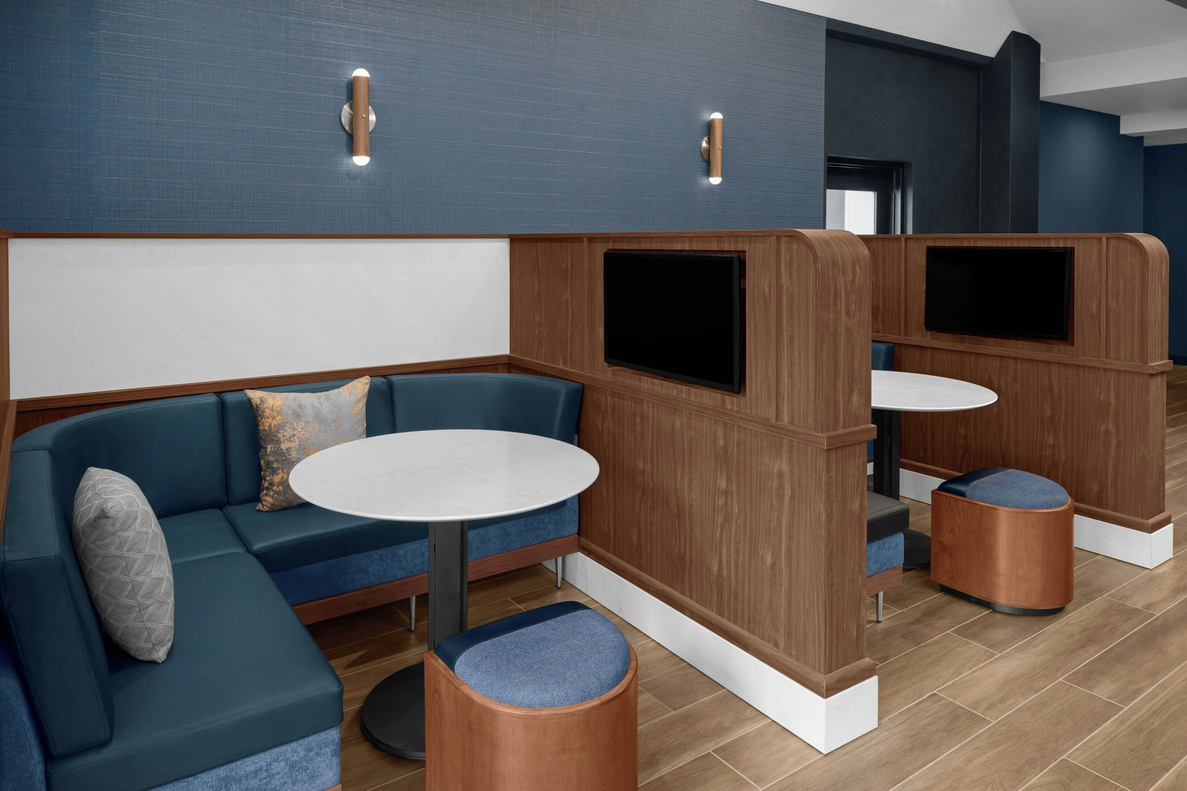 A modern lounge area with a blue sofa, a round table, and wooden partitions.
