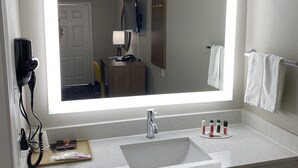 A modern bathroom with a large mirror, a sink, and a vanity. - Days Inn by Wyndham Lake Charles (Lake Charles)