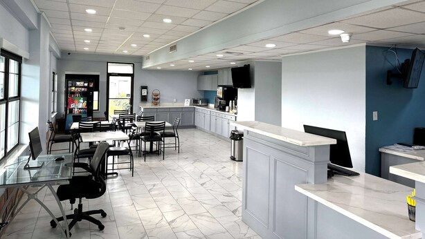 A modern office space with a reception desk, a dining area with tables and chairs, and a kitchen area with appliances. - Days Inn by Wyndham Lake Charles (Lake Charles)