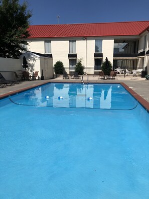 Una piscina al aire libre de temporada, sillones reclinables de piscina