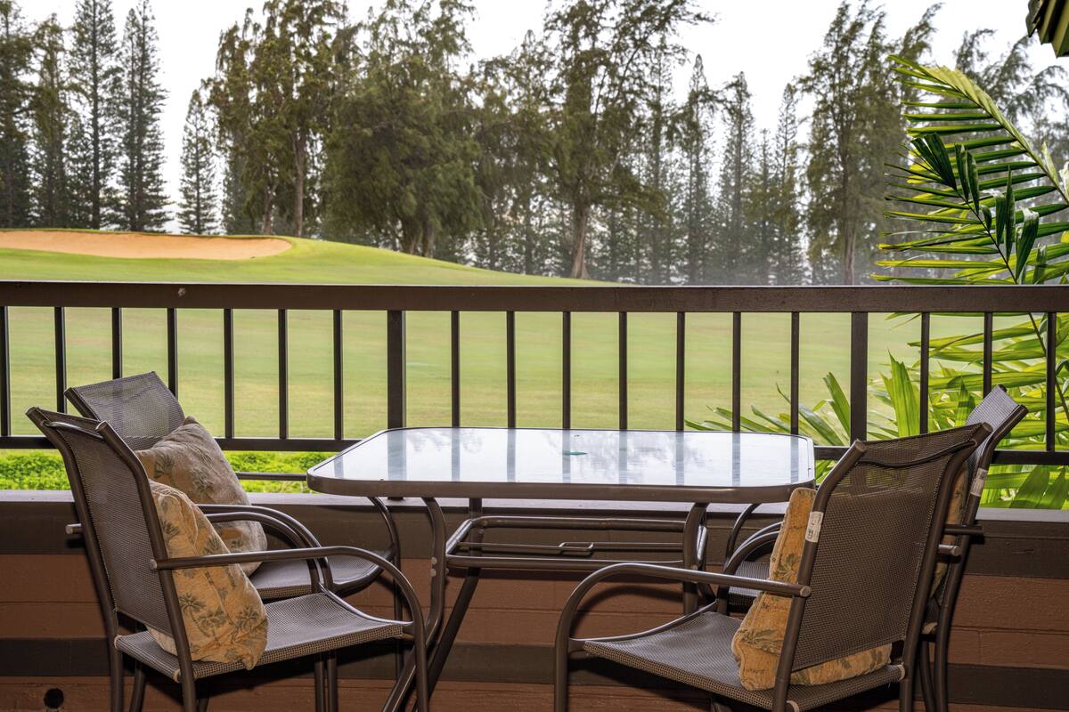 Ein Balkon mit Tisch und zwei Stühlen mit Blick auf einen Golfplatz.
