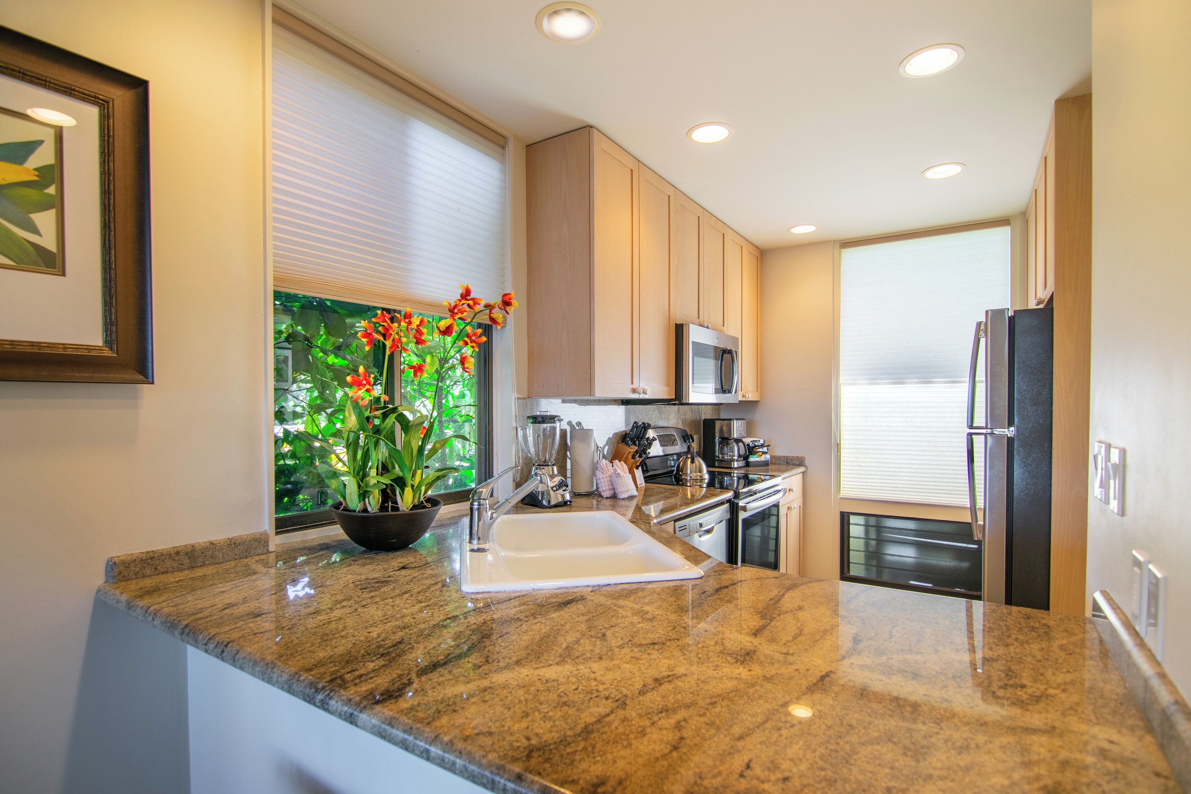 Una cocina moderna con encimeras de granito, microondas integrado y refrigerador de acero inoxidable.