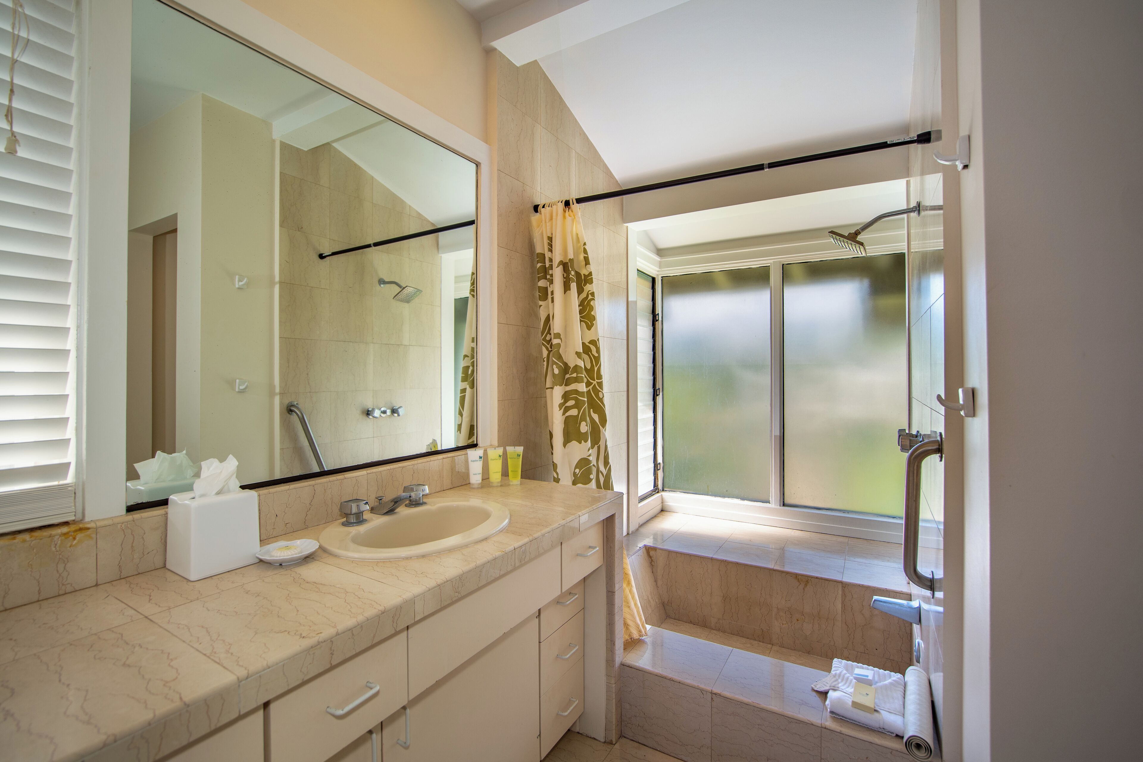 A modern bathroom with a large mirror, a sink, and a shower.