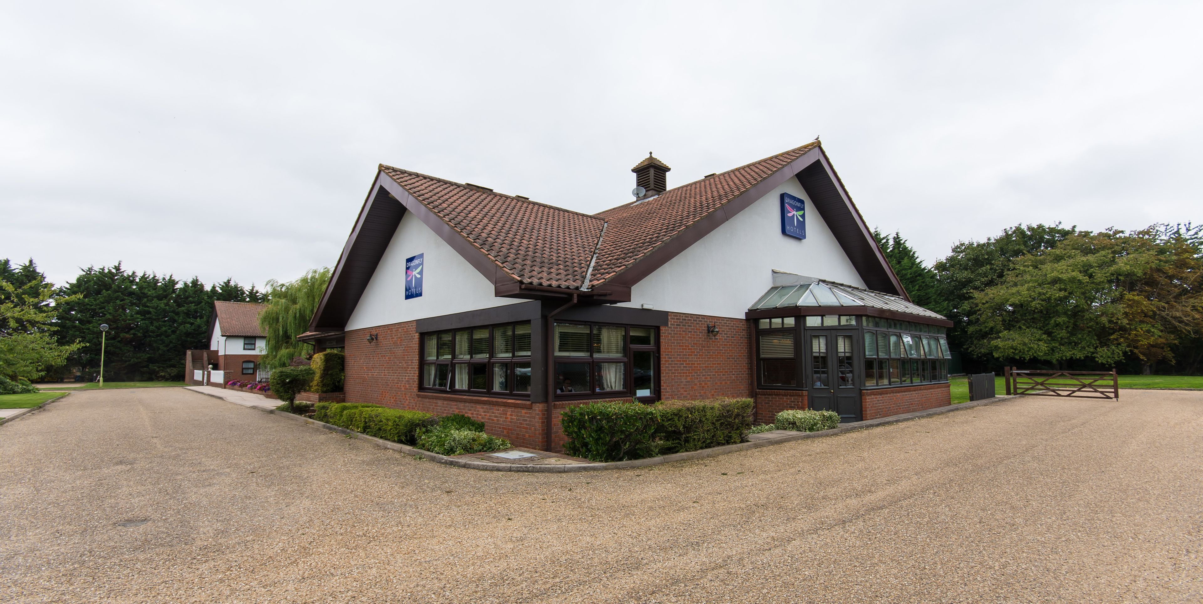 A hotel with a distinctive triangular roof, a covered entrance, and a gravel driveway.