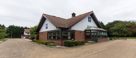 A hotel with a distinctive triangular roof, a covered entrance, and a gravel driveway.