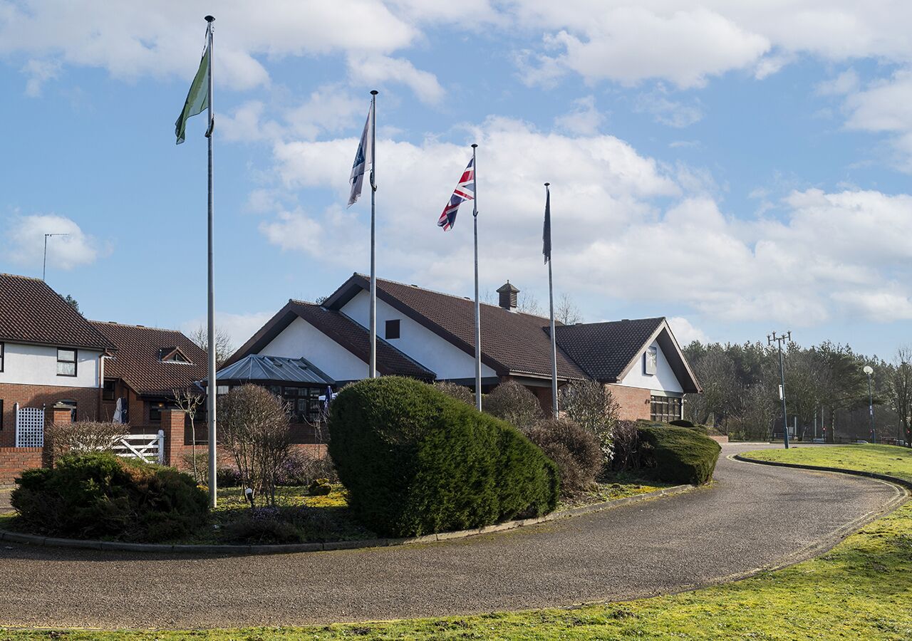 Un quartier résidentiel avec des maisons, une allée gravillonnée et plusieurs drapeaux flottant sur des mâts.