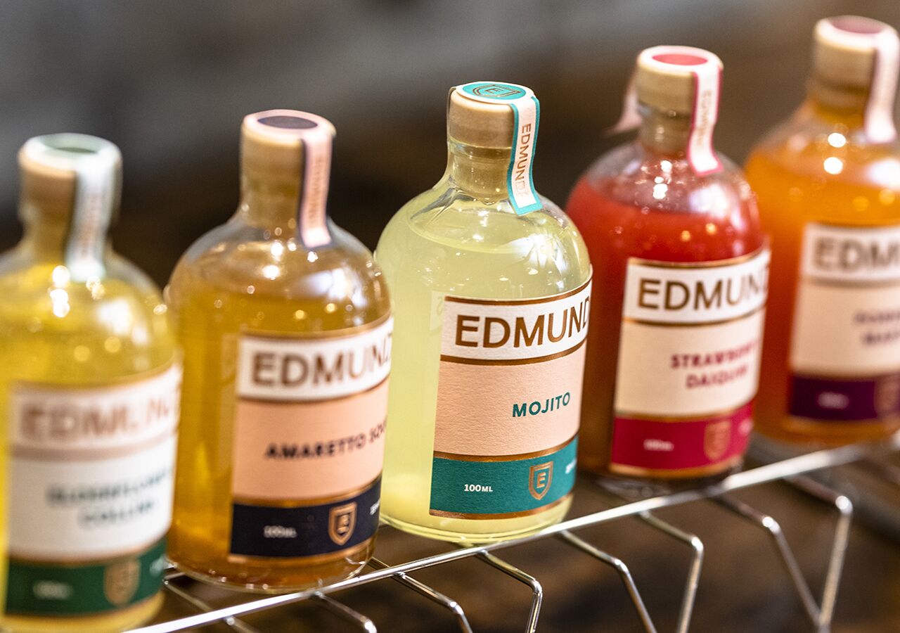 Una estantería con varias botellas de bebidas de la marca Edmunt.