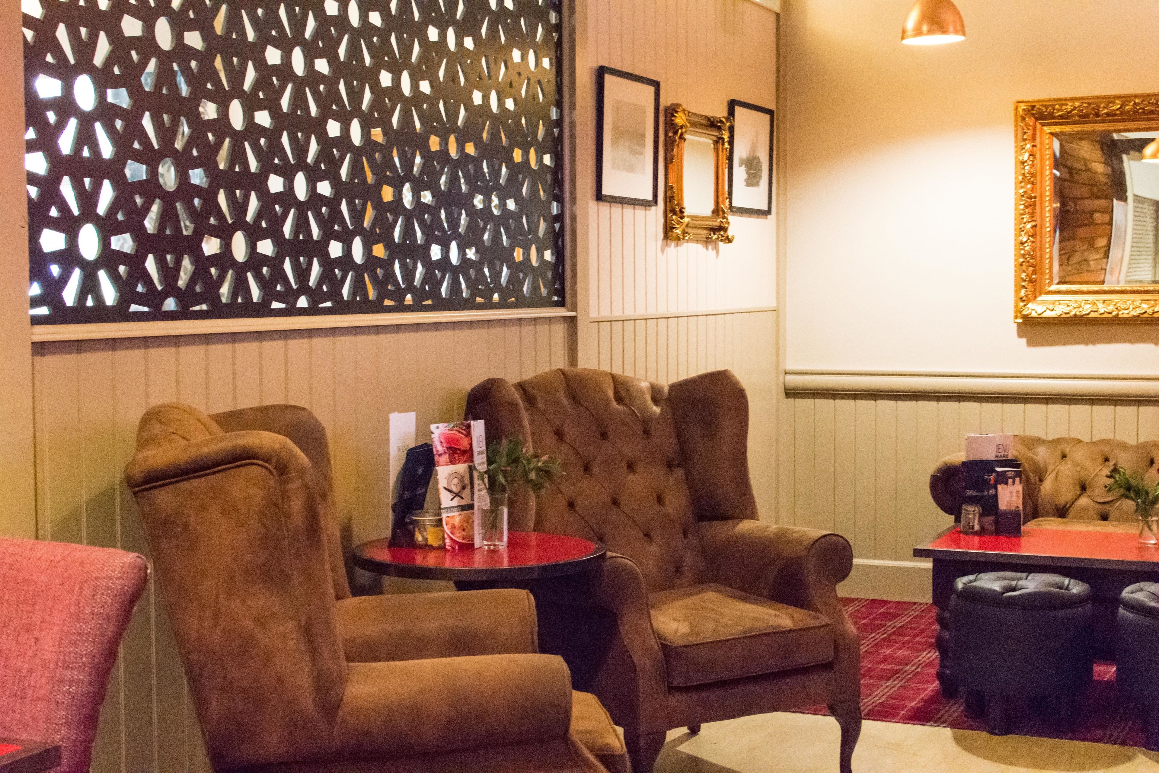 A hotel lobby with a red carpet, a decorative wall, and a tufted sofa.