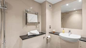 A modern bathroom with a shower, toilet, sink, and a large mirror.