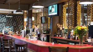 A bar area with a red counter, wooden chairs, and a TV screen mounted on the wall. - Dragonfly Hotel King's Lynn (King's Lynn)