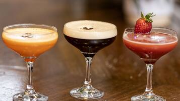 Drei Cocktails in Martini-Gläsern auf einer Holztischplatte.