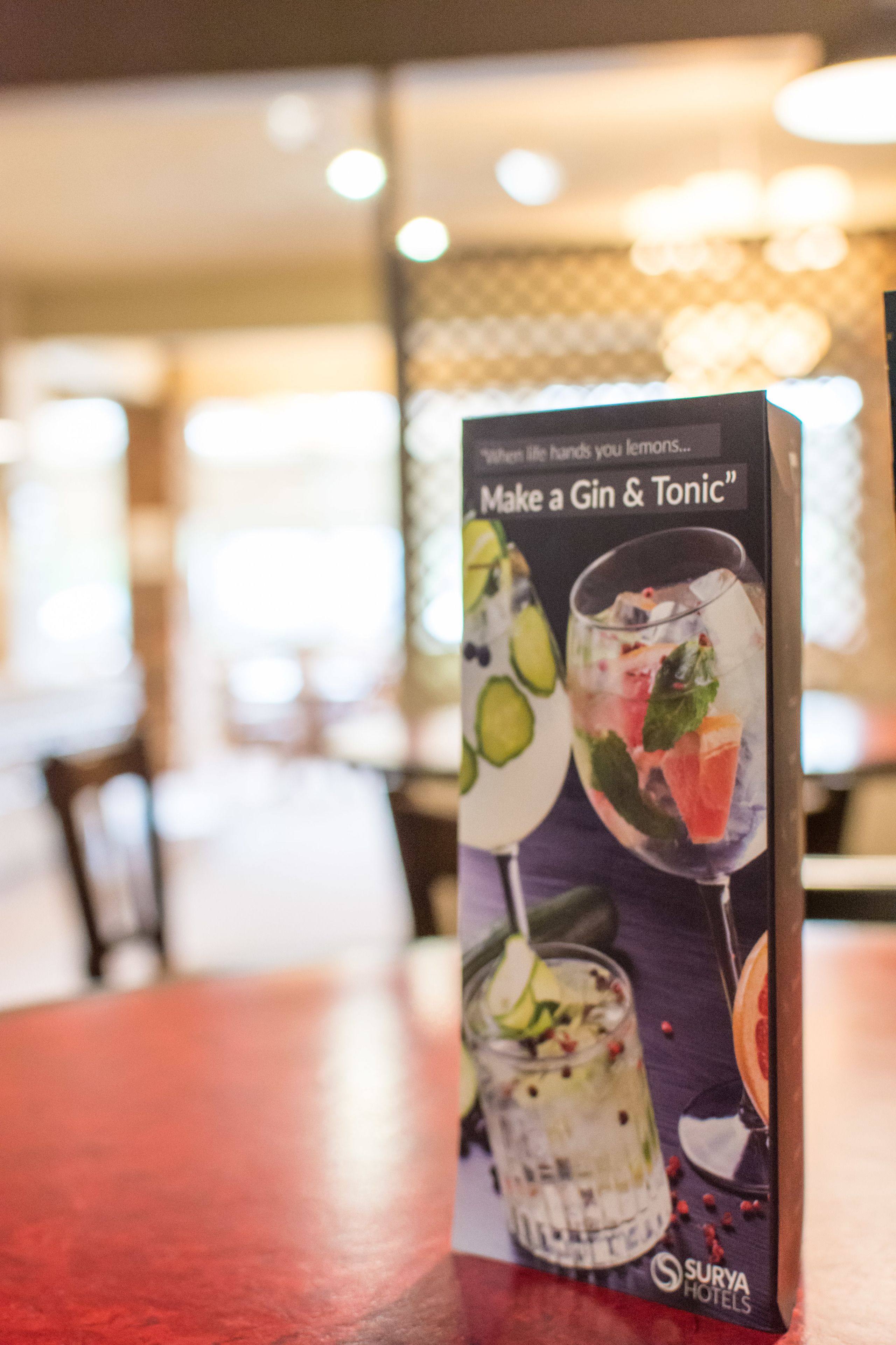 Un panneau affichant un menu avec une recette de boisson intitulée « Préparez un gin tonic » dans les hôtels Surya.